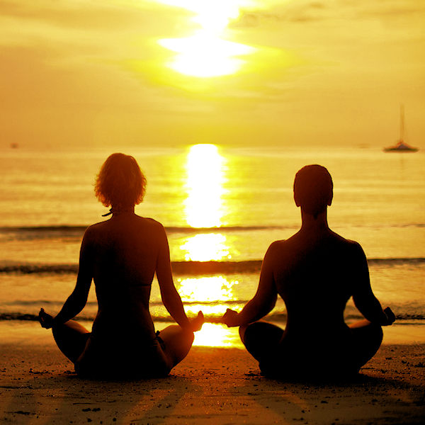 couple meditating on the beach